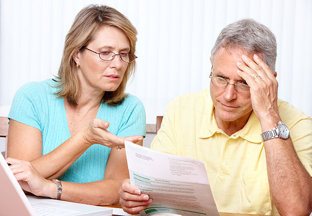 Senior Couple worried and reading a paper